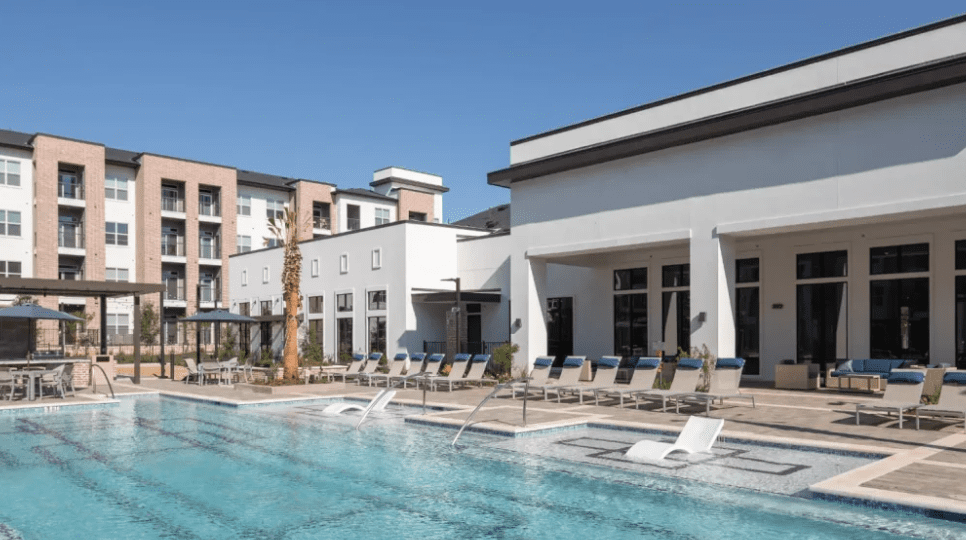 A pool with chairs and umbrellas in the background.